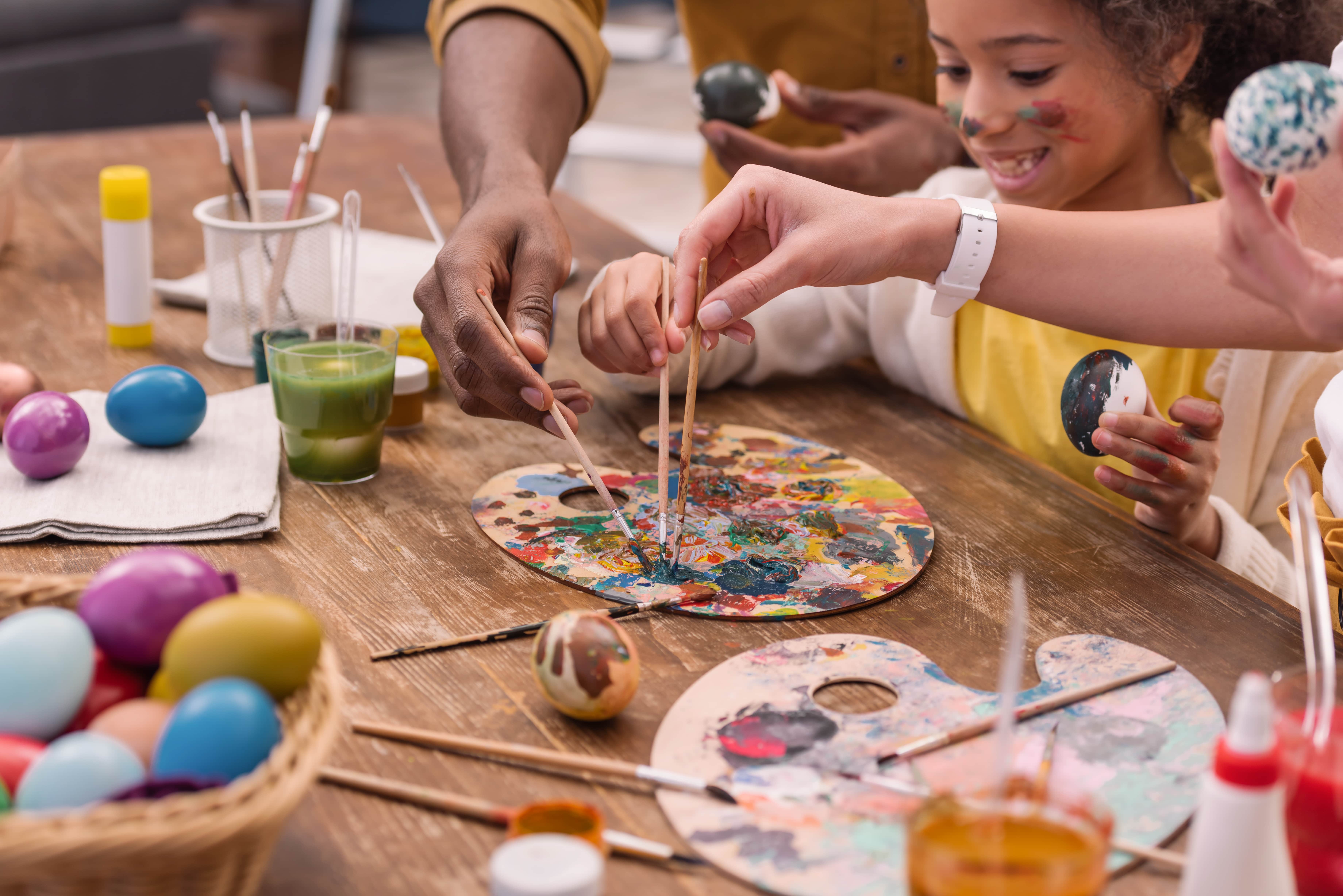 A family painting eggs and enjoying other Easter crafts for kids.